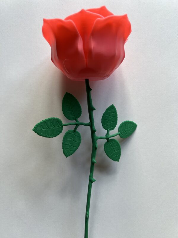 A 3D-printed rose with a bright red bloom and green stem, complete with detailed leaves and thorns, displayed against a plain white background